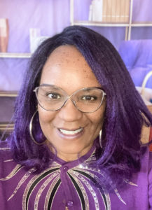 Dr. Raedorah Stewart, Black woman with purple hair, glasses and sweater